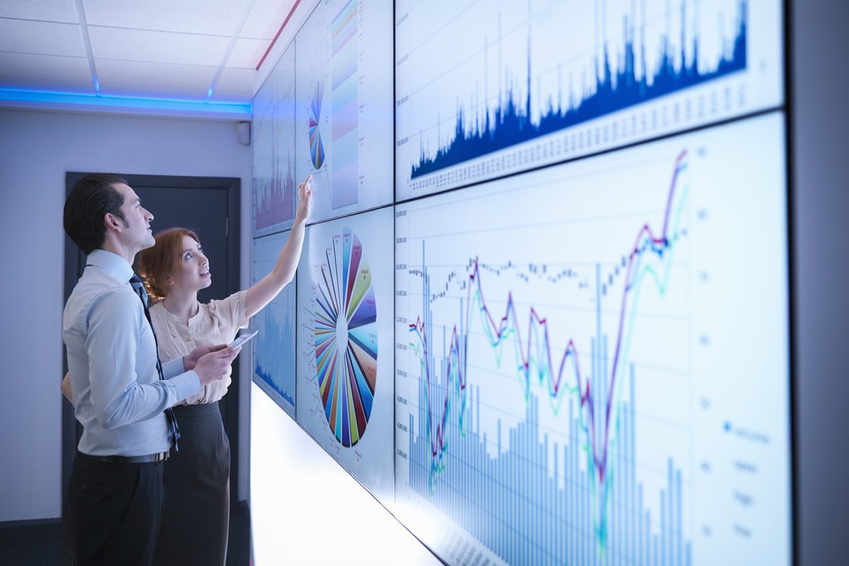 Business colleagues studying graphs on screen in meeting room