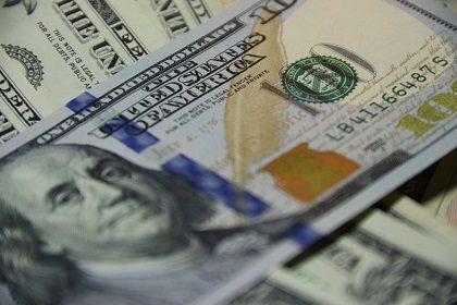 A close-up of a U.S. one hundred dollar bill placed on top of other U.S. currency notes.