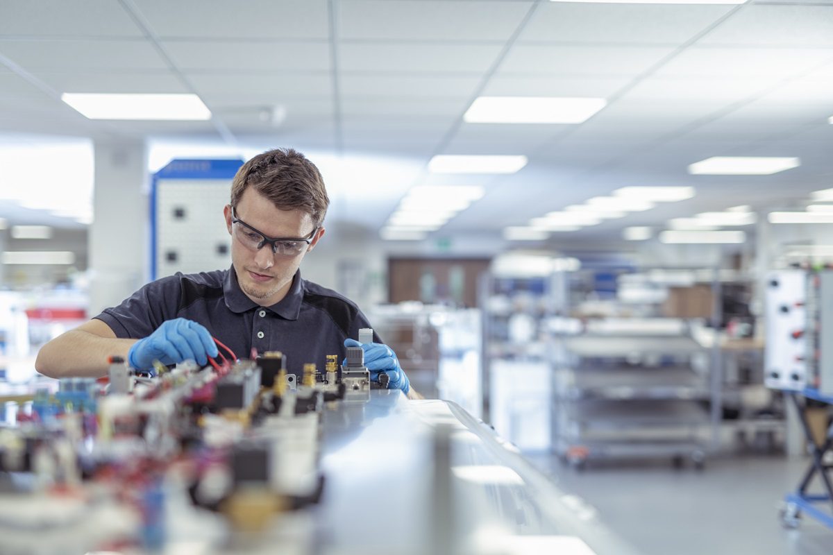 Apprentice engineer working in medical electronics machinery manufacturing factory